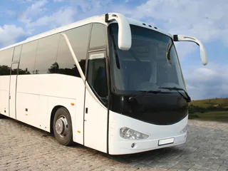 Weißer Reisebus von vorn auf gepflastertem Platz