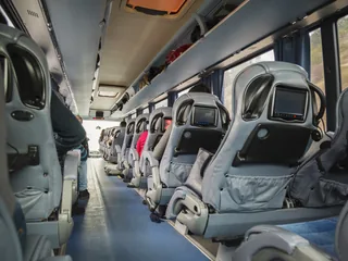 Innenraum eines Reisebusses mit Sitzreihen und Monitoren